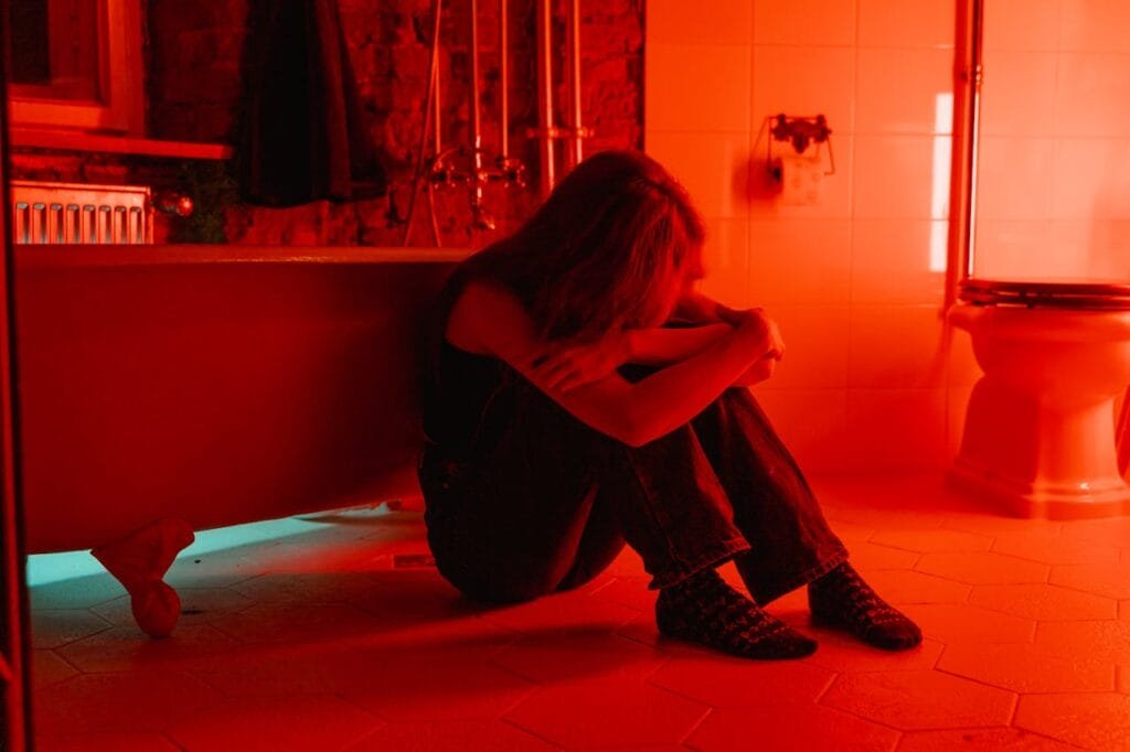 Woman crying alone on the bathroom floor, heal your abandonment issues with inner child therapy
