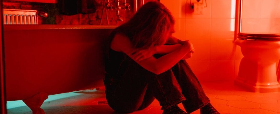 Woman crying alone on the bathroom floor, heal your abandonment issues with inner child therapy