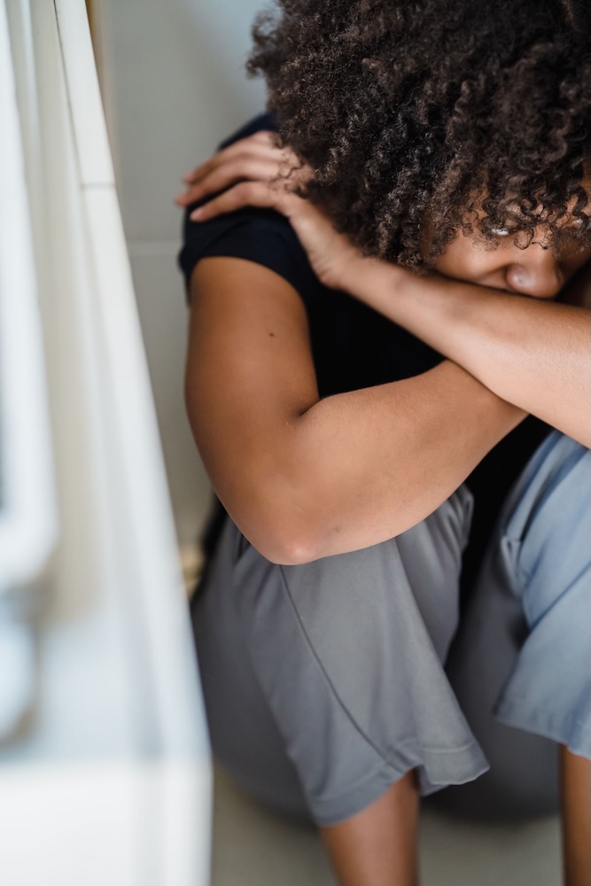 Image of a woman looking afraid hugging her knees, anxiety hypnotherapy with Rowenna