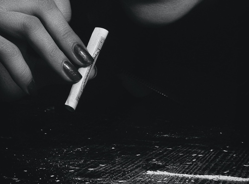 Image of a woman with a rolled up note and a line of powder on the table, hypnosis for addiction with Rowenna Clifford