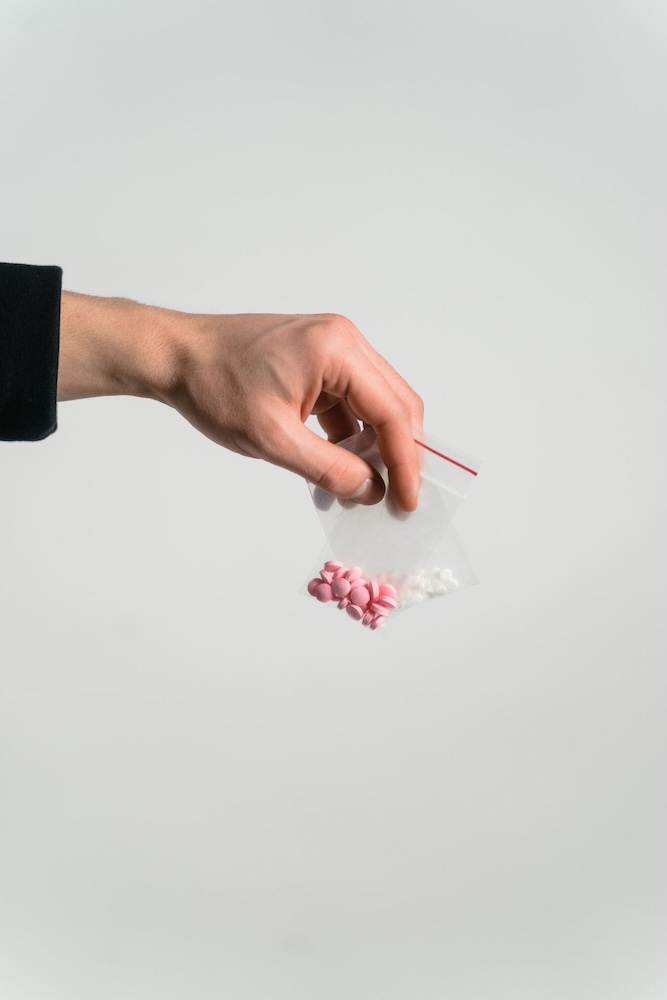 Image of a mans hand holding two bags of pills, hypnosis for addiction with Rowenna Clifford
