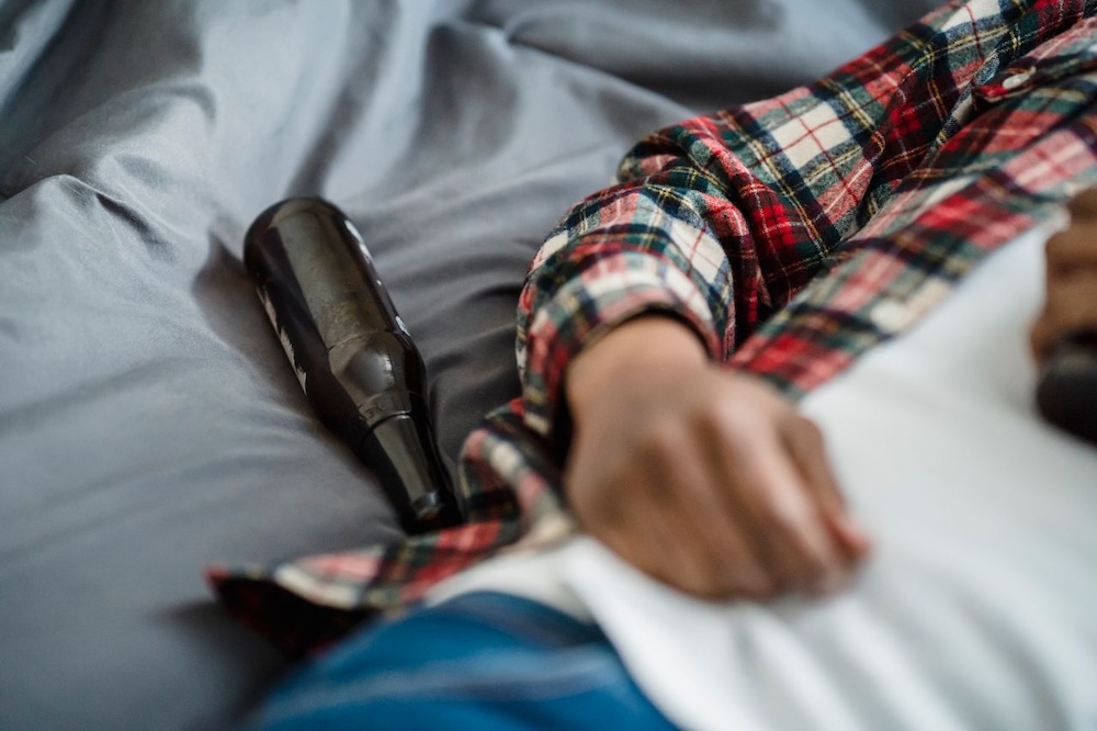 Image of a man asleep with an empty beer bottle next to him, stop drinking hypnotherapy with Rowenna