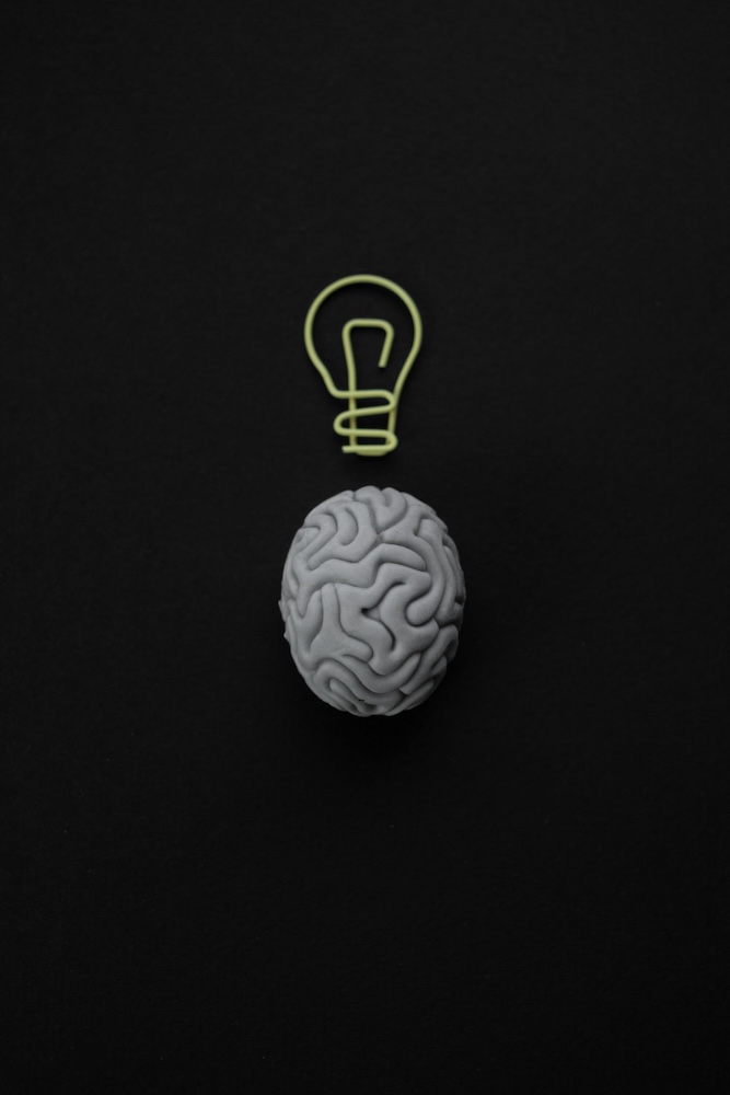 Image of a brain on a black background with a lightbulb drawn above it, what is cognitive hypnotherapy by Rowenna Clifford